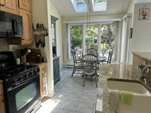 kitchen featuring light stone counters, sink, black appliances, and vaulted ceiling with skylight