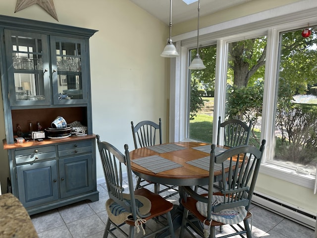 tiled dining space featuring a baseboard heating unit, a skylight, and a healthy amount of sunlight