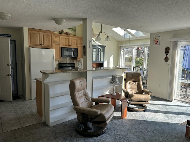 kitchen with a kitchen bar, a wealth of natural light, black appliances, and lofted ceiling with skylight