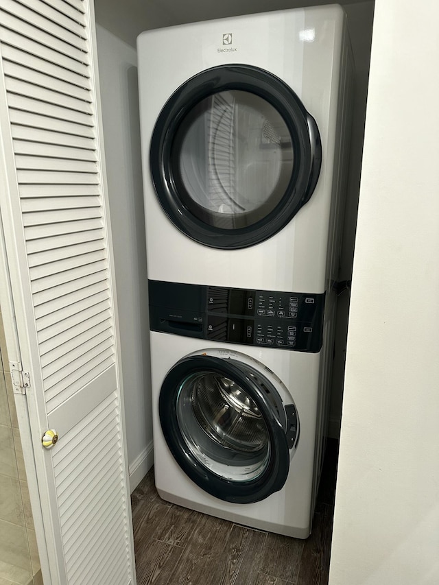 laundry room with stacked washer / drying machine and dark hardwood / wood-style floors