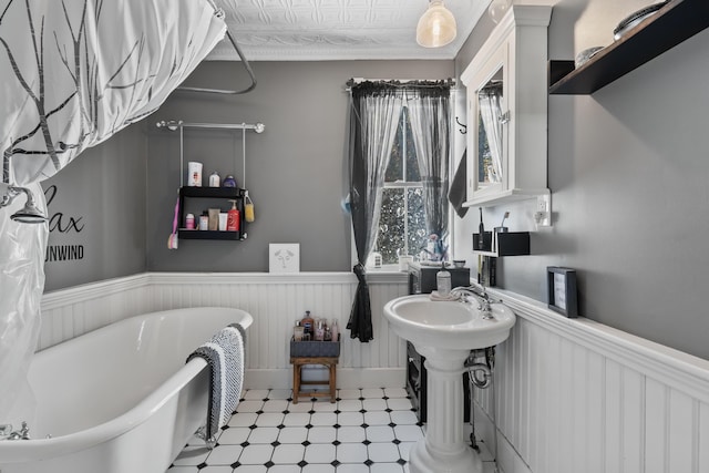 full bathroom with a soaking tub, a wainscoted wall, and tile patterned floors