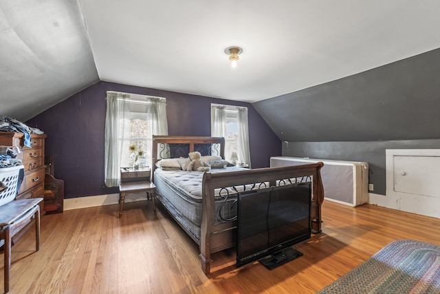 bedroom with vaulted ceiling, baseboards, and wood finished floors