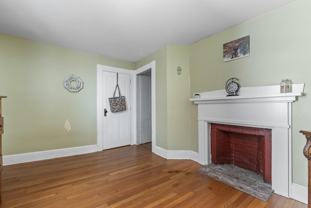 unfurnished living room featuring wood-type flooring, a fireplace, and baseboards