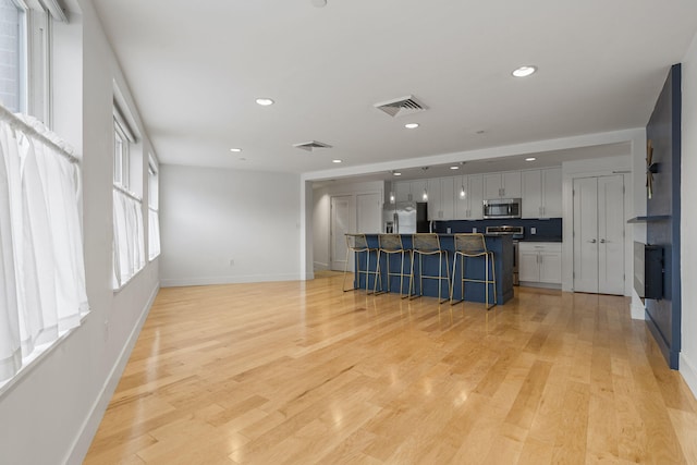 kitchen featuring a center island, light hardwood / wood-style floors, a breakfast bar area, and stainless steel appliances