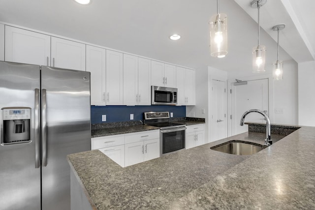 kitchen with stainless steel appliances, sink, dark stone countertops, white cabinets, and hanging light fixtures