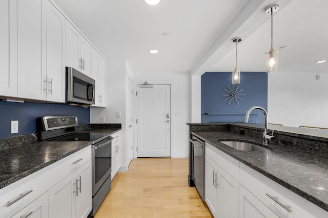 kitchen featuring white cabinets, appliances with stainless steel finishes, decorative light fixtures, and sink