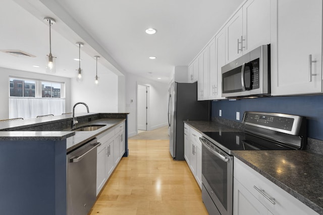 kitchen with white cabinetry, sink, hanging light fixtures, appliances with stainless steel finishes, and light wood-type flooring