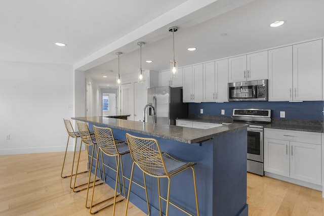 kitchen featuring white cabinetry, light hardwood / wood-style flooring, an island with sink, and stainless steel appliances