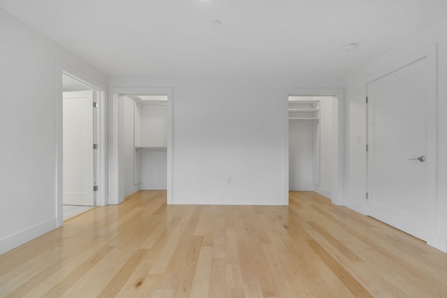 unfurnished bedroom with light wood-type flooring and a spacious closet