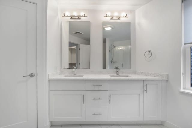 bathroom featuring tile patterned flooring, a shower, and vanity