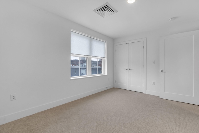 unfurnished bedroom with light colored carpet and a closet