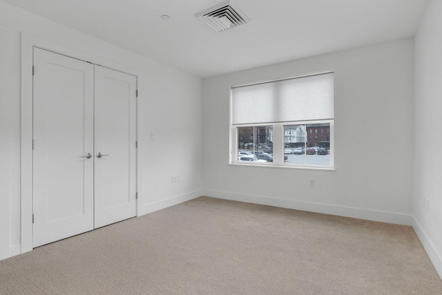 unfurnished bedroom with light carpet and a closet