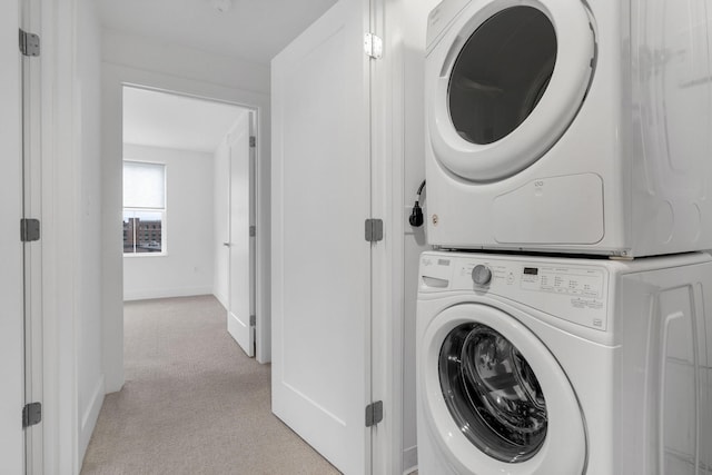 laundry area featuring light carpet and stacked washer and clothes dryer