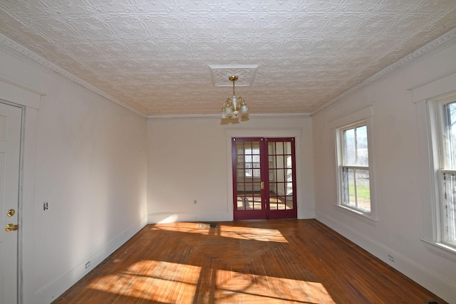 empty room with a chandelier, ornamental molding, a textured ceiling, and french doors