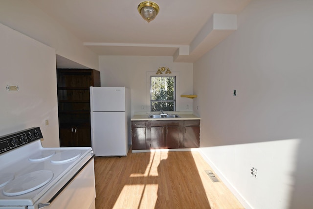 kitchen featuring light wood-type flooring, white appliances, and sink