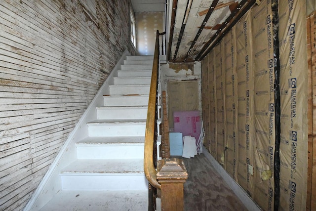 stairway featuring wood walls