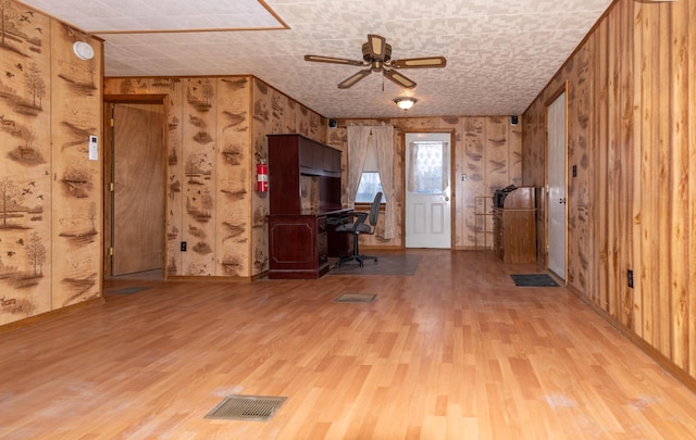 unfurnished office with wood-type flooring, ceiling fan, and wood walls