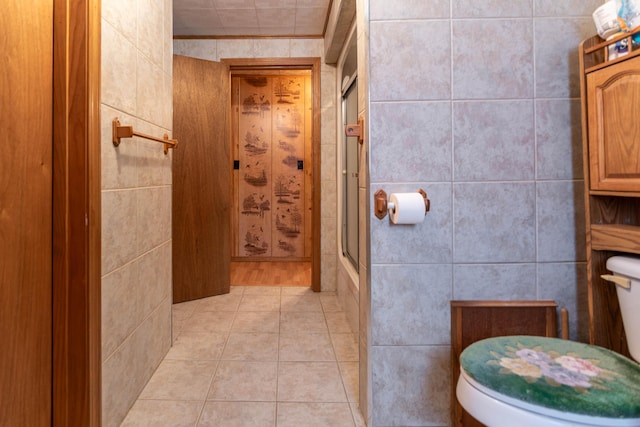 bathroom with tile patterned floors, an enclosed shower, tile walls, and toilet