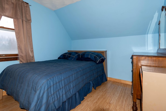 bedroom featuring light hardwood / wood-style floors and lofted ceiling