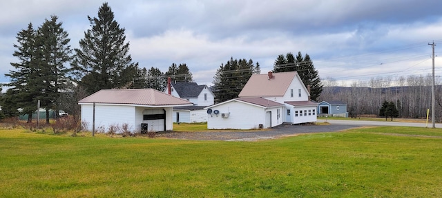 exterior space with a lawn, a garage, and an outdoor structure