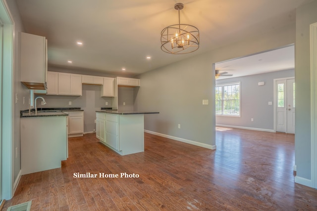 kitchen with a kitchen island, decorative light fixtures, wood-type flooring, sink, and white cabinets