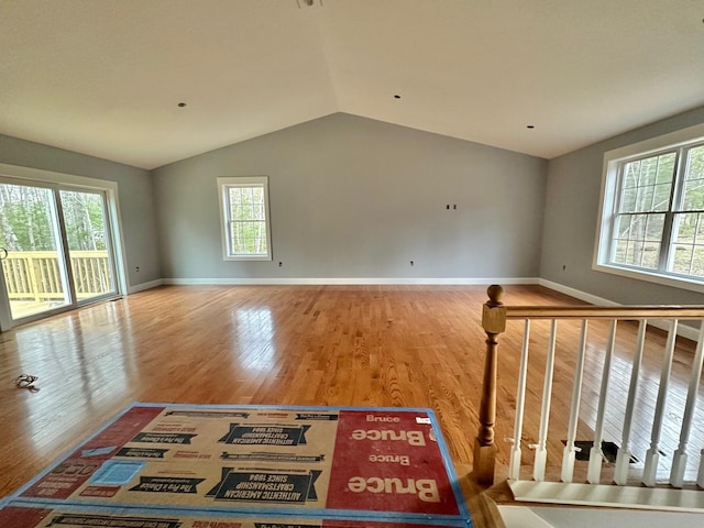 unfurnished room featuring lofted ceiling, baseboards, and wood finished floors