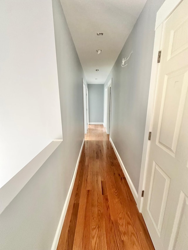 hallway featuring wood finished floors and baseboards