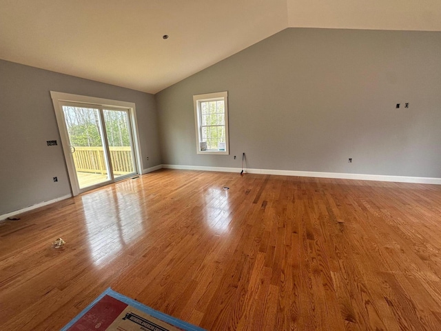 empty room featuring vaulted ceiling, wood finished floors, and baseboards