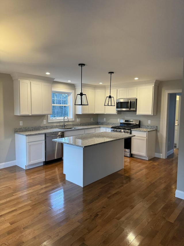 kitchen with decorative light fixtures, a center island, stainless steel appliances, and white cabinetry