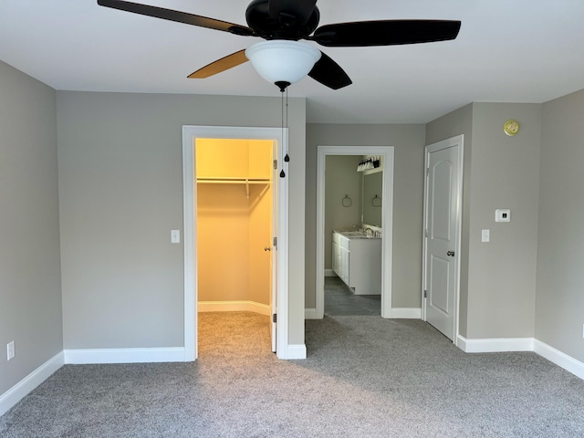 unfurnished bedroom featuring connected bathroom, ceiling fan, a walk in closet, light carpet, and a closet