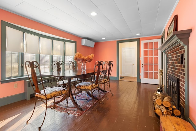 dining area featuring a fireplace, wood-type flooring, a wall mounted air conditioner, and crown molding