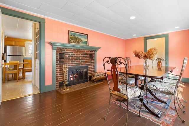 dining room featuring a fireplace, dark hardwood / wood-style flooring, and crown molding