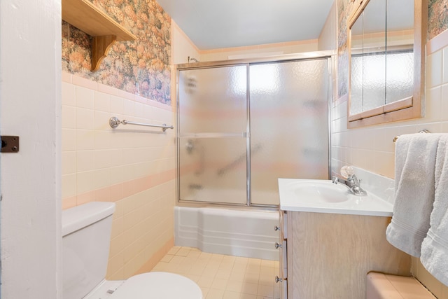 full bathroom with vanity, toilet, tile walls, and enclosed tub / shower combo