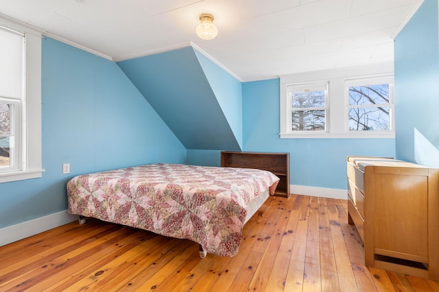 bedroom with lofted ceiling, light hardwood / wood-style flooring, and ornamental molding