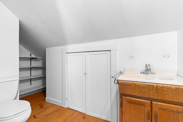 bathroom with vanity, toilet, wood-type flooring, and lofted ceiling