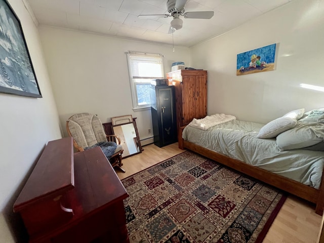 bedroom with light hardwood / wood-style floors, a baseboard radiator, ceiling fan, and ornamental molding