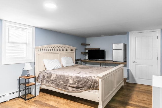 bedroom featuring hardwood / wood-style flooring, white refrigerator, and a baseboard heating unit