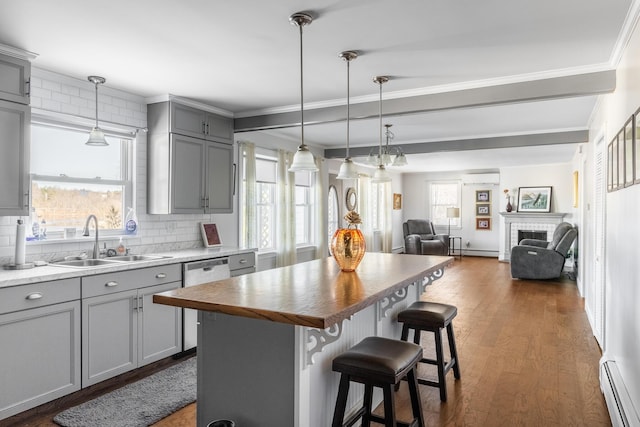 kitchen with sink, a center island, a kitchen breakfast bar, baseboard heating, and dark hardwood / wood-style floors