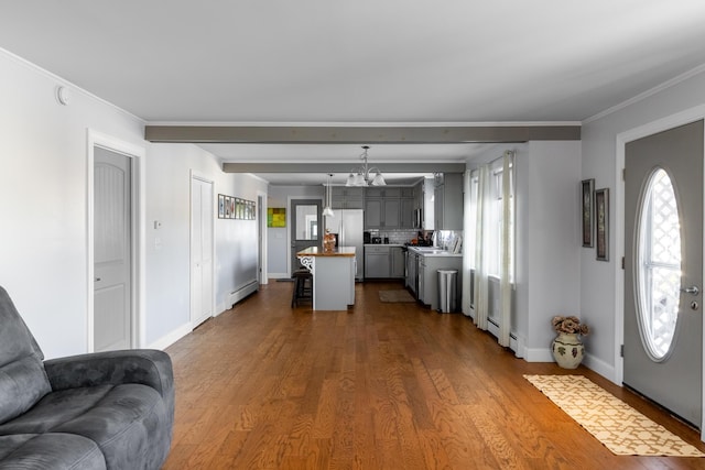 living room featuring hardwood / wood-style floors, a baseboard radiator, an inviting chandelier, and crown molding