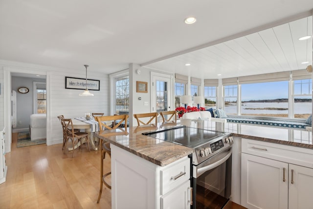 6 Brooks St, Kennebunkport, ME 04046 - kitchen featuring stainless steel electric range, white cabinetry, light stone counters, light wood-style flooring, and hanging light fixtures