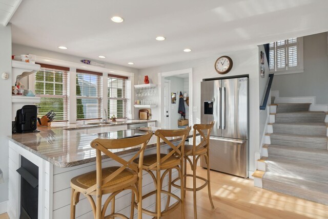 6 Brooks St, Kennebunkport, ME 04046 - kitchen featuring stainless steel refrigerator with ice dispenser, open shelves, a breakfast bar, light stone counters, and recessed lighting