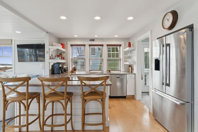 6 Brooks St, Kennebunkport, ME 04046 - kitchen featuring appliances with stainless steel finishes, open shelves, recessed lighting, light wood finished floors, and light stone countertops