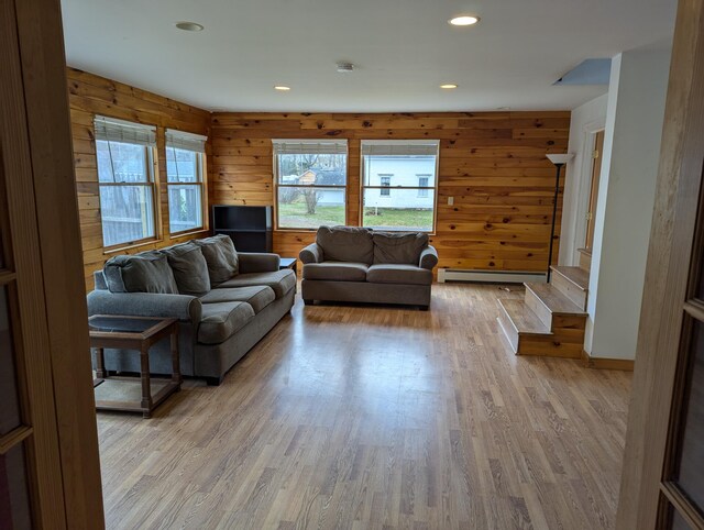 living room featuring a baseboard radiator, light hardwood / wood-style flooring, and wooden walls