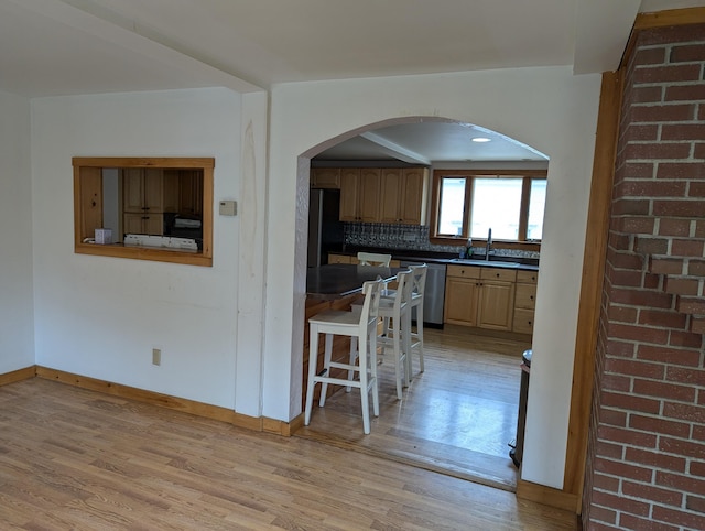 1 Branch St, Camden, ME 04843 - kitchen featuring stainless steel dishwasher, light wood-style flooring, dark countertops, freestanding refrigerator, and arched walkways