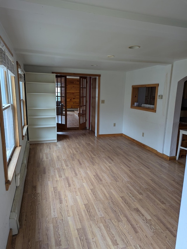 unfurnished living room featuring light wood-type flooring and a baseboard heating unit