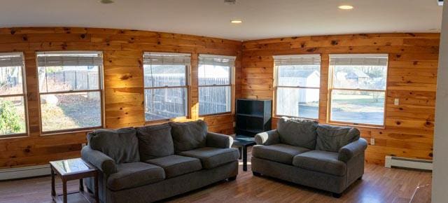 living room featuring hardwood / wood-style floors, a baseboard heating unit, and wood walls