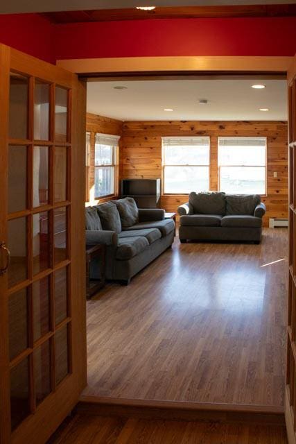 living room featuring french doors, dark hardwood / wood-style flooring, and wooden walls