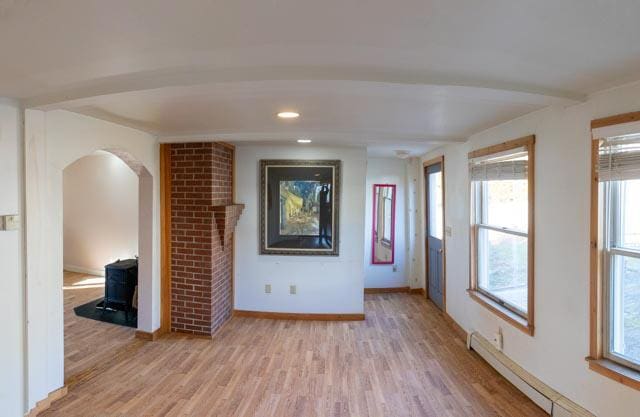 unfurnished living room featuring light wood-type flooring and a baseboard heating unit