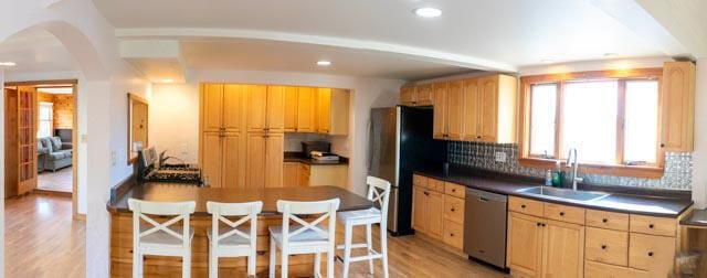 1 Branch St, Camden, ME 04843 - kitchen with stainless steel appliances, light wood-style flooring, tasteful backsplash, arched walkways, and light brown cabinetry