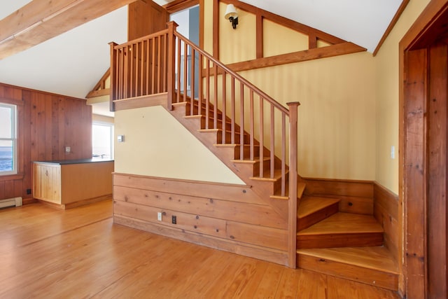 stairs featuring wooden walls, hardwood / wood-style floors, and lofted ceiling